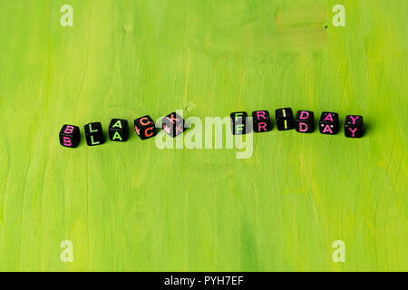 Text `Black Friday` composed of small black blocks with colored letters on green background. Stock Photo